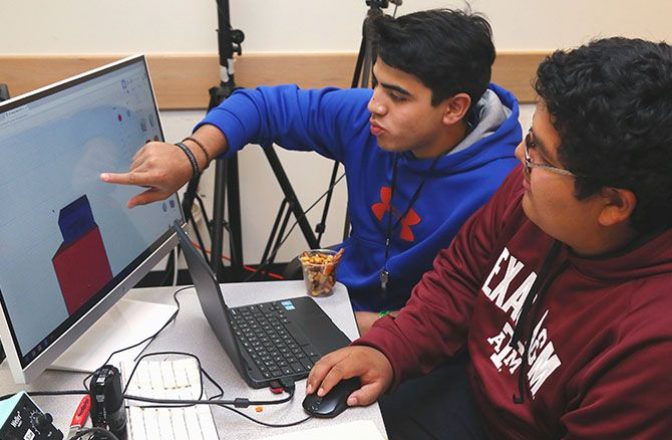 High school students work on design plans from a computer in a studio