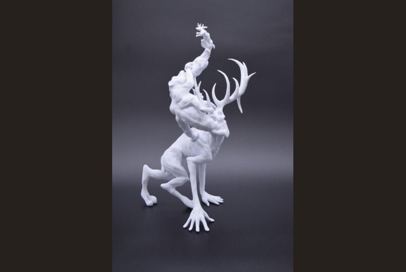 3D printed sculpture of a jackalope coming out of the mouth of a dog, which is coming out of a hippo, which is coming out of a creature with antlers and humanoid hands.