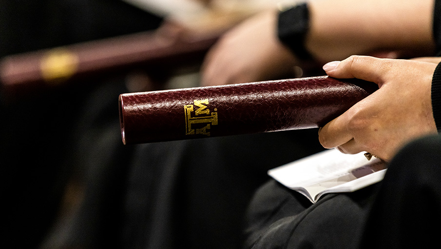hands holding a Texas A&M diploma tube