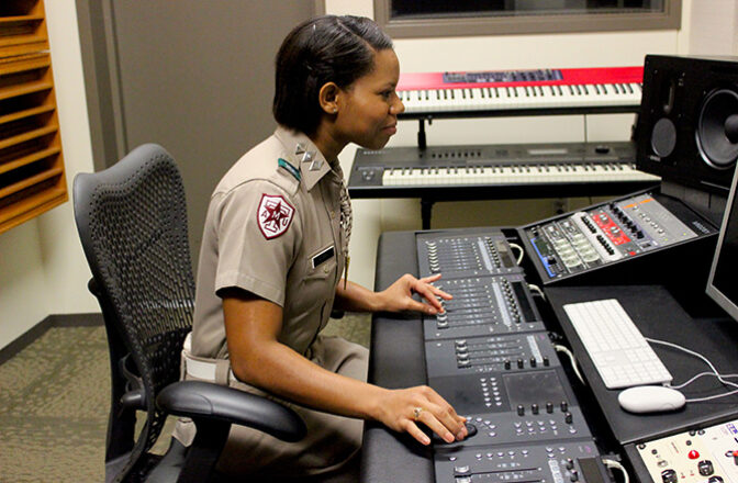 A corps cadet works in a lighting booth