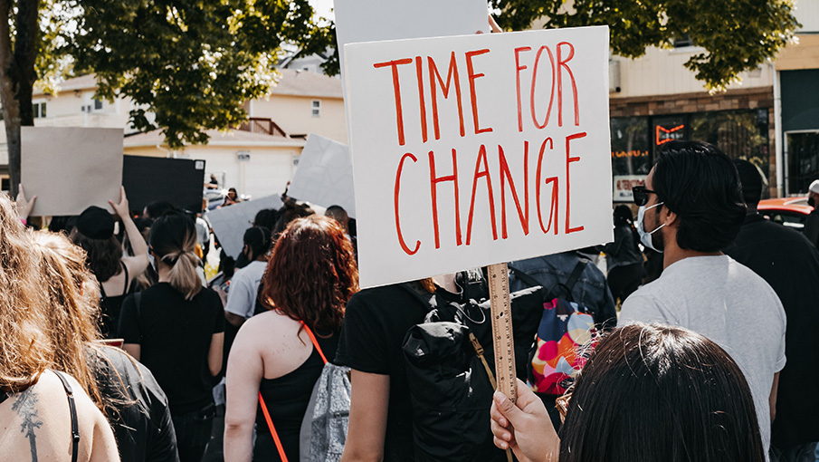 Person holding a sign that says "time for change" during a protest