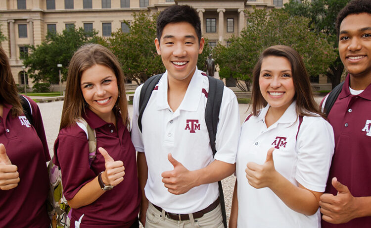 Five students give the Gig 'Em in front of the Academic Building