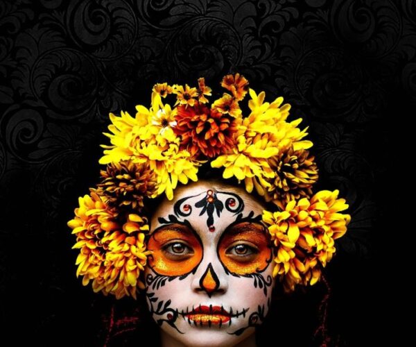 Portrait of a young girl wearing a flower crown, a dress and make-up in style for Dia de los Muertos