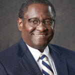 A portrait of a man in a suit, smiling for a photo