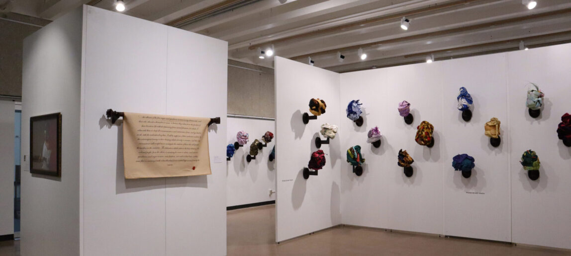 An art exhibit features photography and textile, sculpture and headwraps.