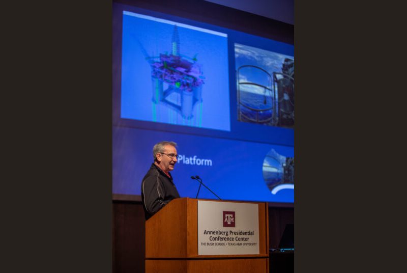 A man stands at a podium giving an academic presentation