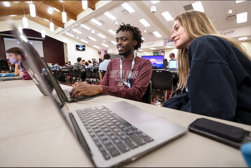 Two college students look at a laptop computer screen at a game jam event.