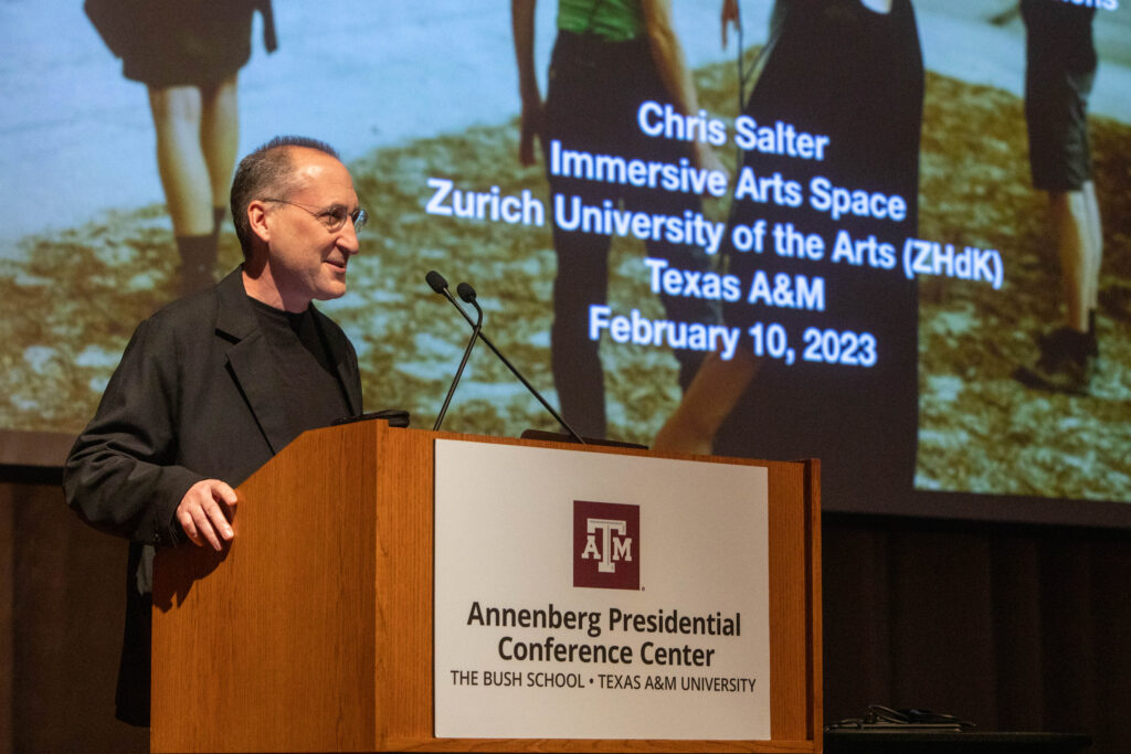 A man stands at a podium giving an academic presentation