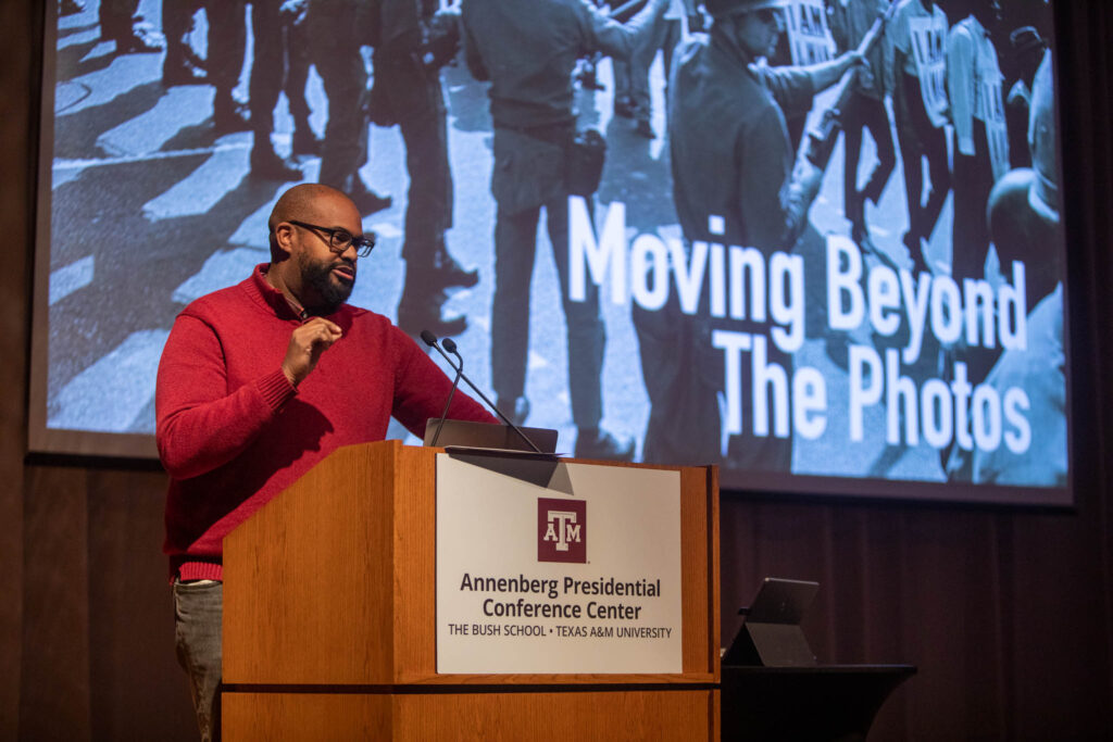 A man stands at a podium giving an academic presentation