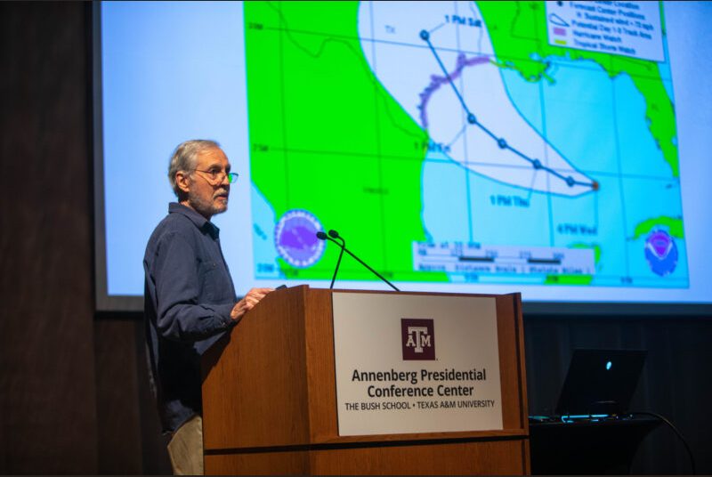 A man stands at a podium giving an academic presentation