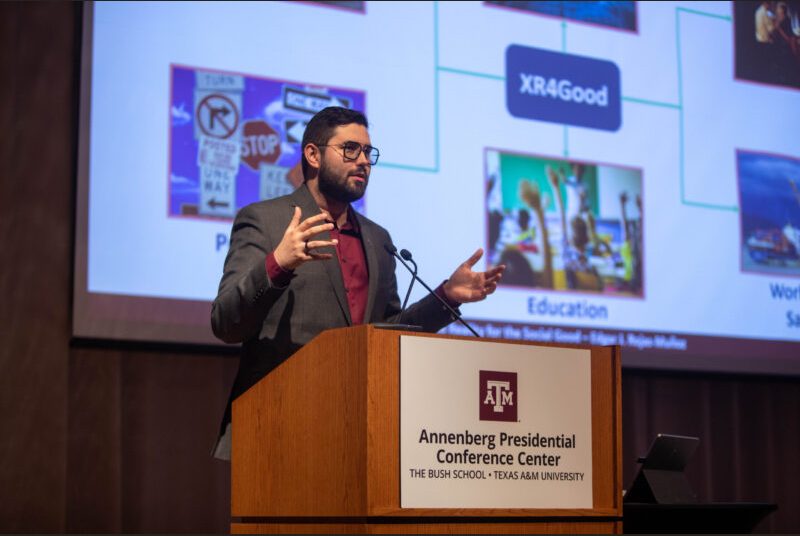 A man stands at a podium giving an academic presentation