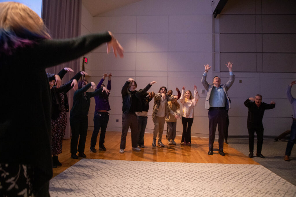 People raise their arms while participating in an improvisation exercise
