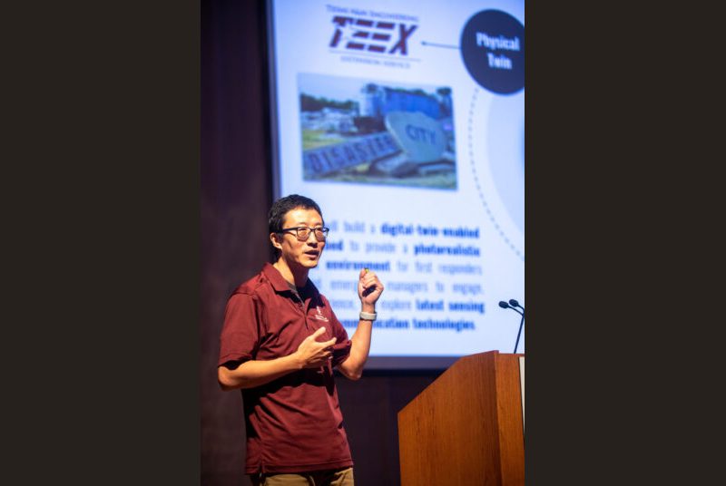 A man stands at a podium giving an academic presentation