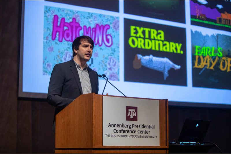 A man stands at a podium giving an academic presentation