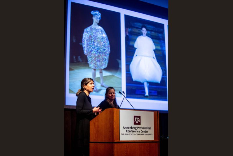 Two professors stand at a podium giving an academic presentation