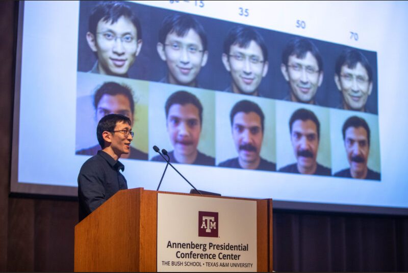 A man stands at a podium giving an academic presentation