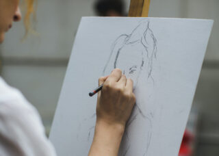 An artist sketches a person on a canvas.