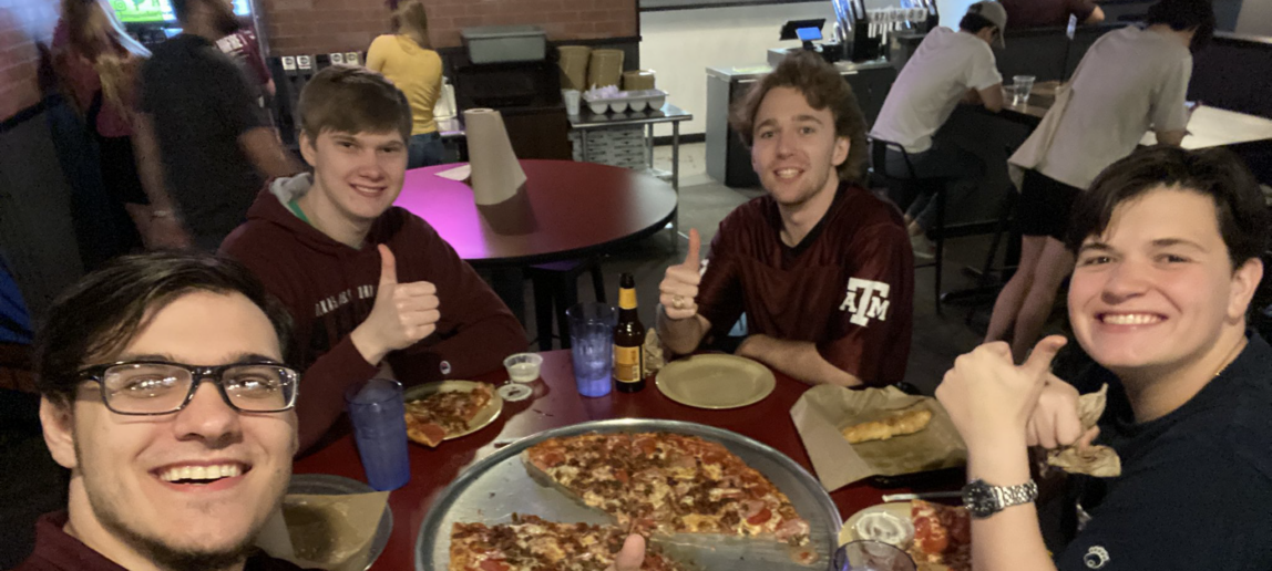 Four members of a college Esports team smile at a pizza restaurant.