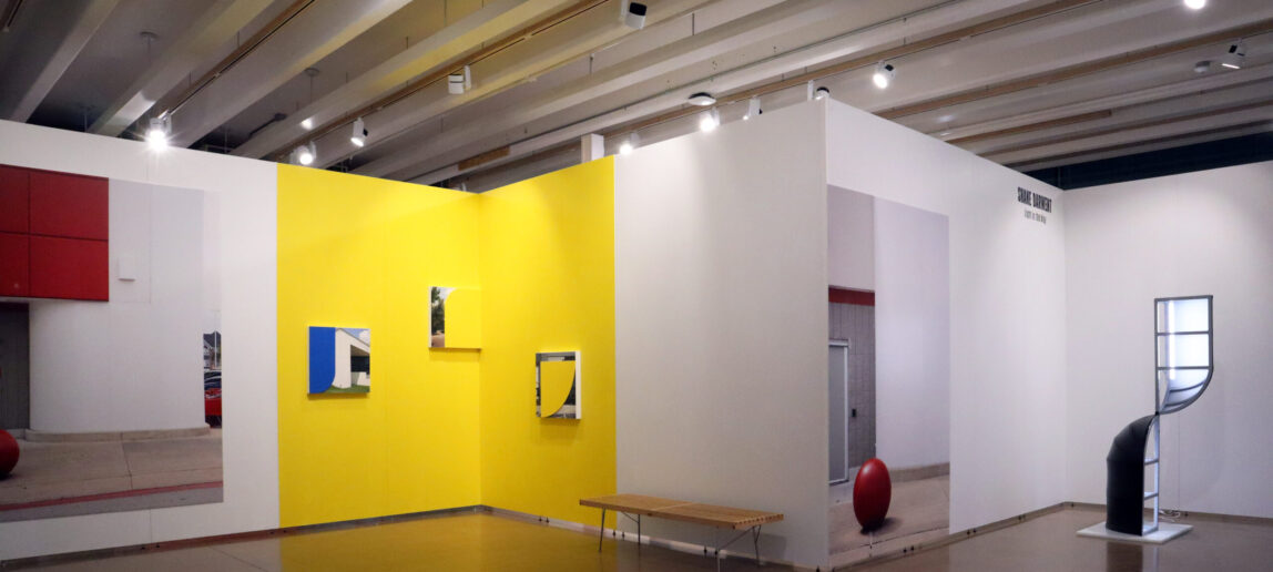Artwork displayed on a yellow wall in an art gallery
