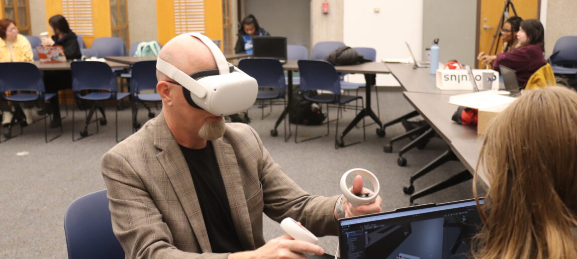 A man wearing virtual reality goggles gestures with the hand controllers