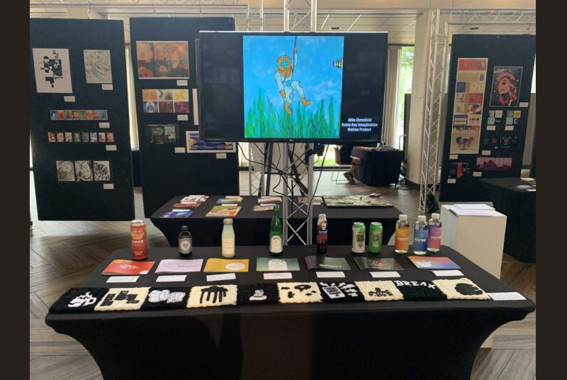 Student artwork including drawings, fabric, bottles, cans and a motion project on display at an art exhibition