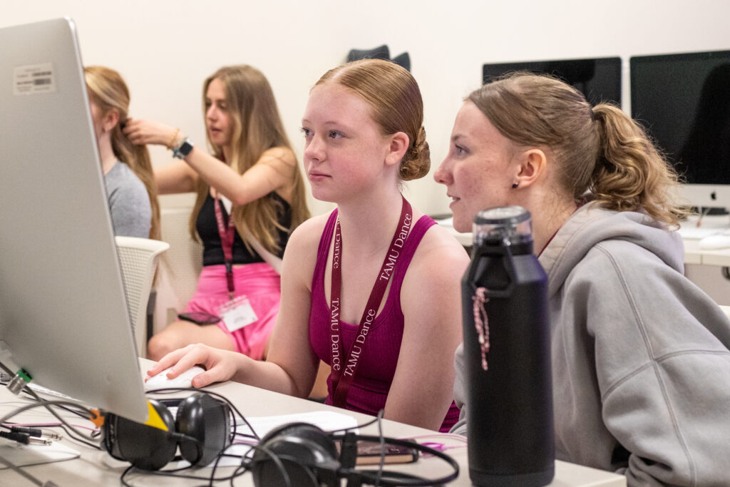 Two high school students watch a video on a computer screen.