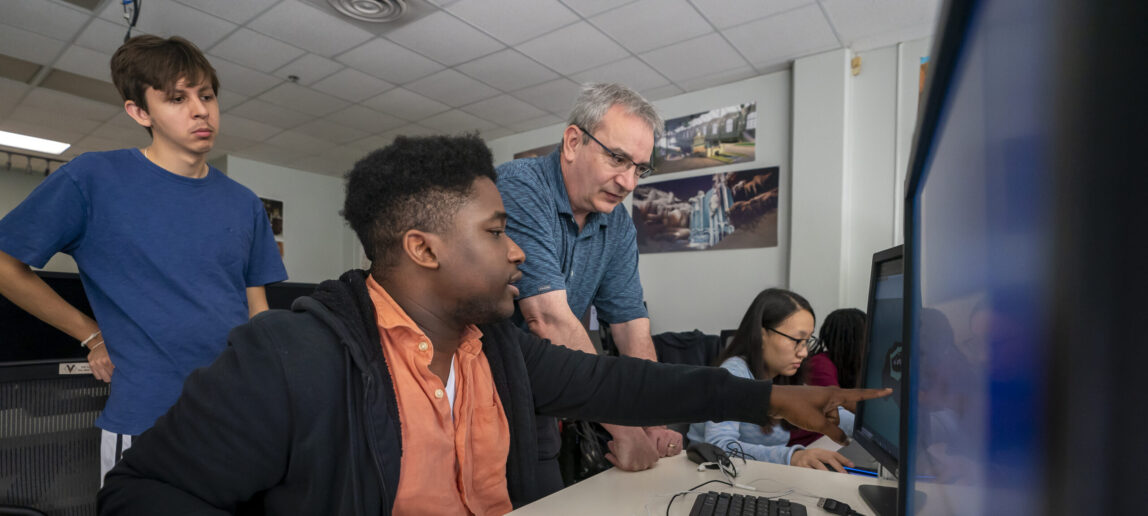 Students work with a professor on a computer game.