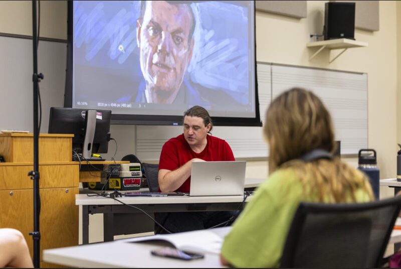 A college professor leads a drawing workshop for college students.