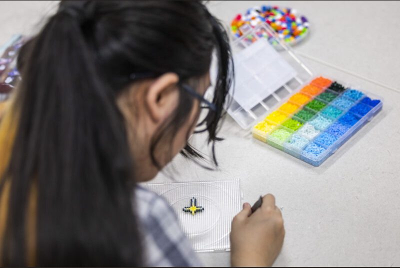 A college student works with beads at an art party.