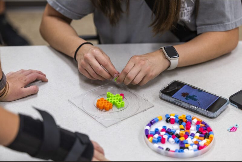 College students participate in a beading craft at an art party.