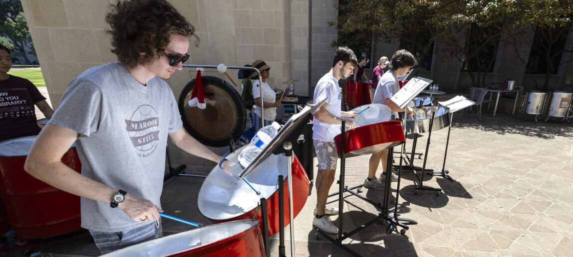 A steel pan ensemble performs in an outdoor courtyard.