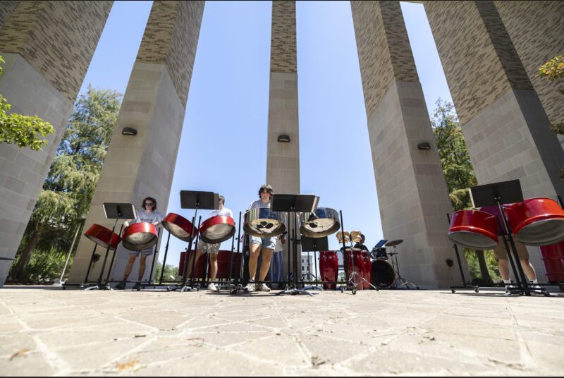 A steel pan ensemble performs in an outdoor courtyard.