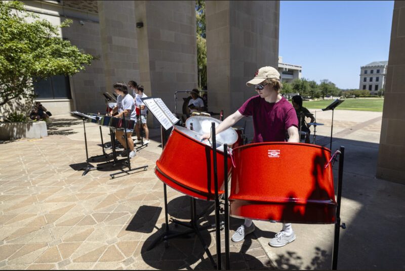 A steel pan ensemble performs in an outdoor courtyard.