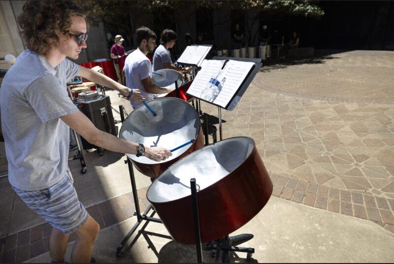 A steel pan ensemble performs in an outdoor courtyard.