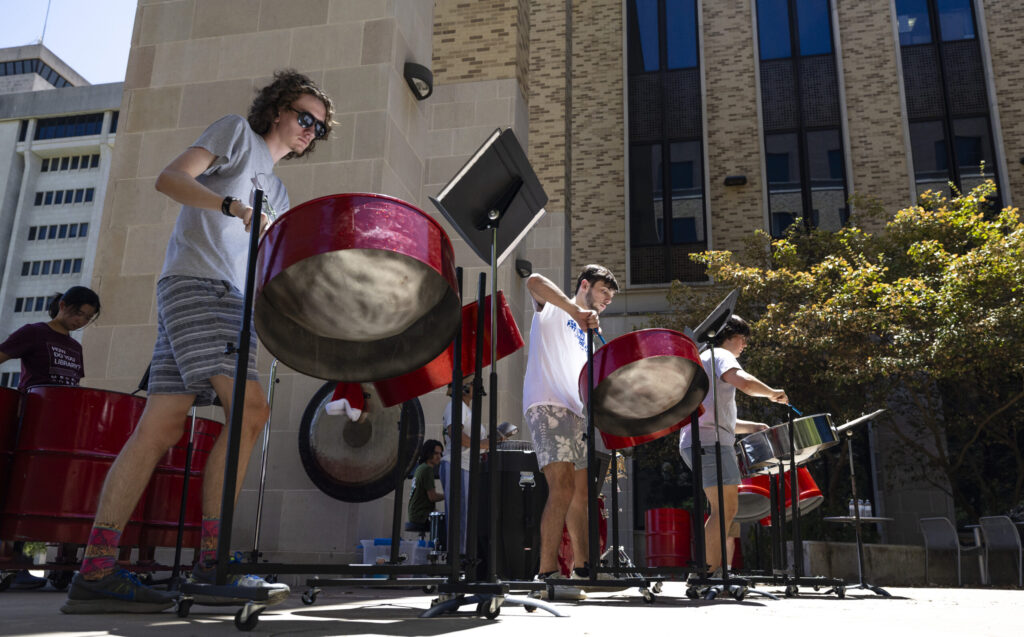 A steel pan ensemble performs in an outdoor courtyard.