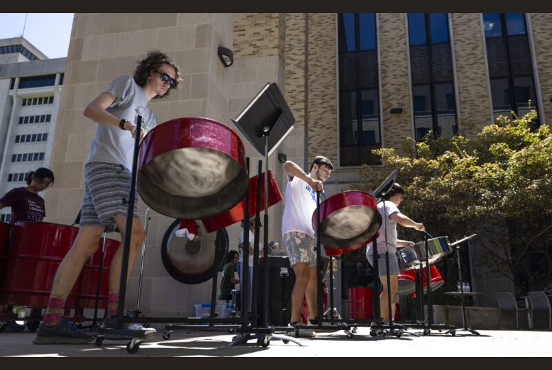 A steel pan ensemble performs in an outdoor courtyard.