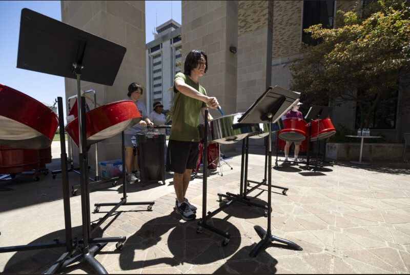 A steel pan ensemble performs in an outdoor courtyard.