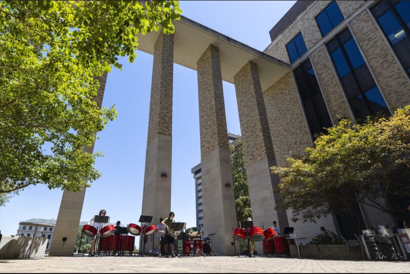 A steel pan ensemble performs in an outdoor courtyard.