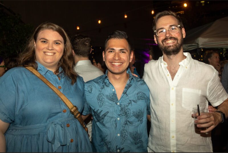 Three people smile for a photo at a party