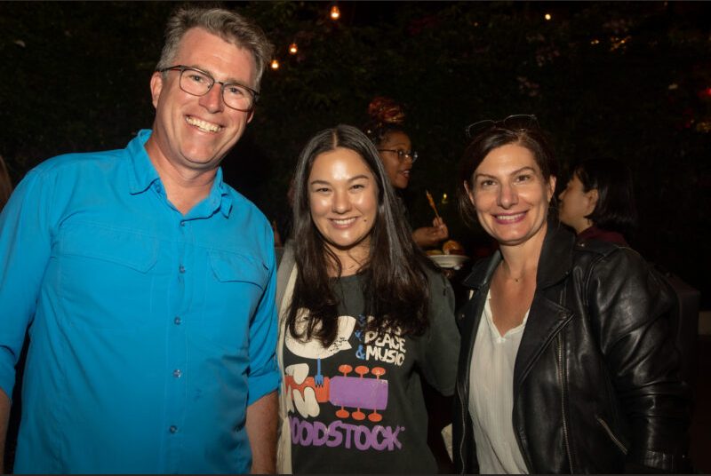 Three people smile for a photo at a party