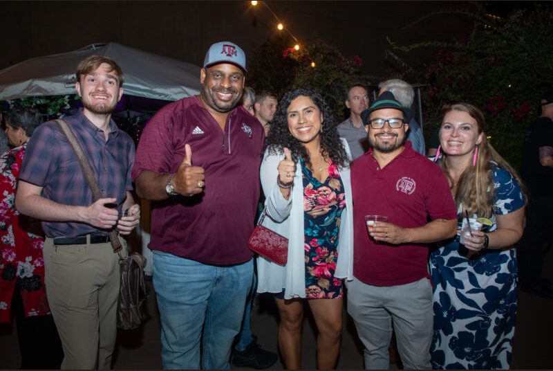 Five people smile for a photo at a party