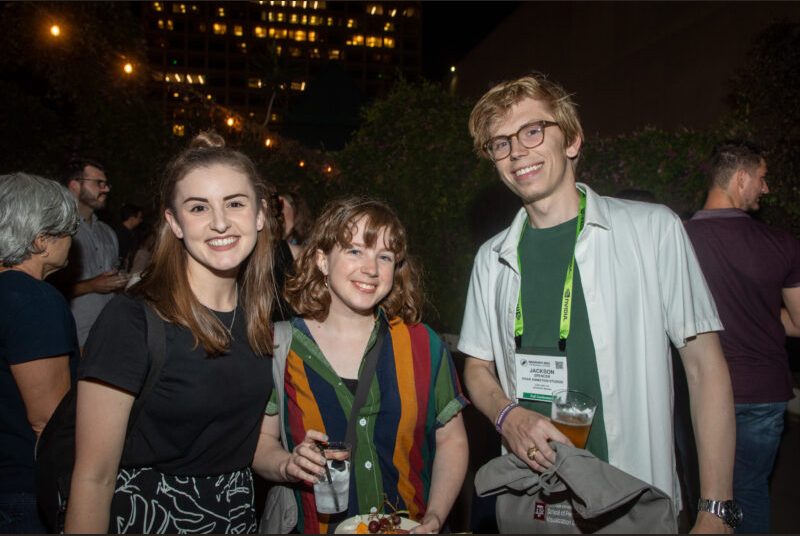 Three people smile for a photo at a party