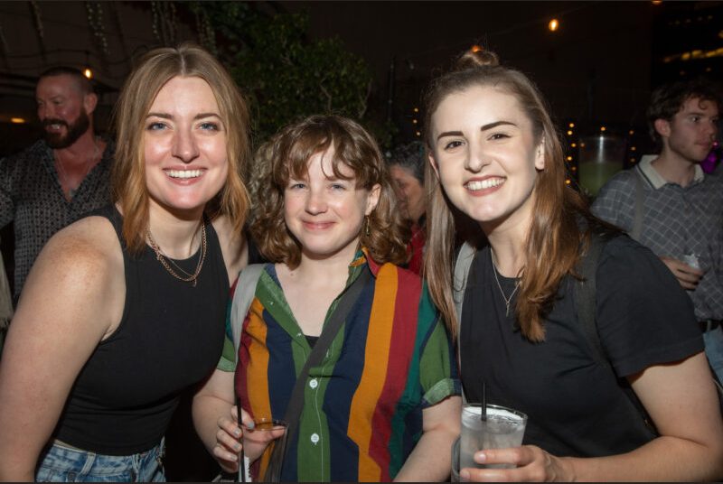 Three people smile for a photo at a party