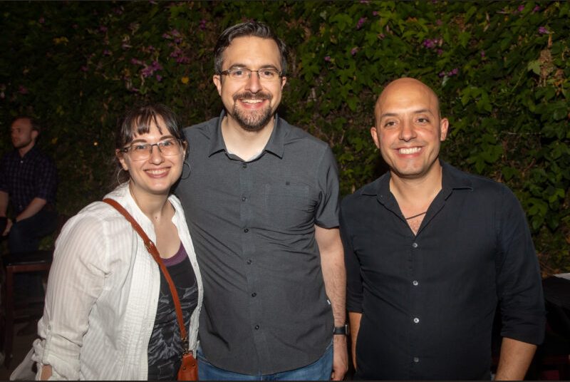 Three people smile for a photo at a party