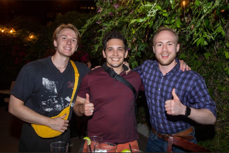 Three people smile for a photo at a party