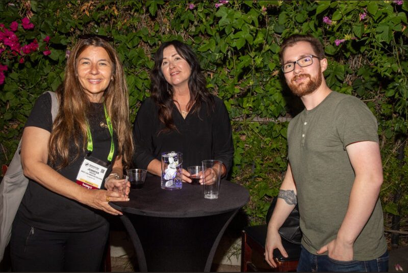 Three people smile for a photo at a party