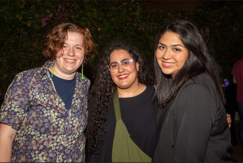 Three people smile for a photo at a party