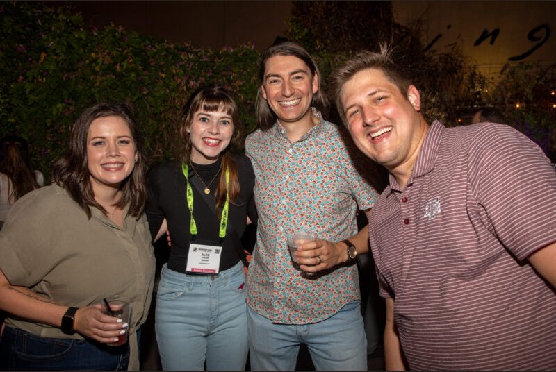 Four people smile for a photo at a party