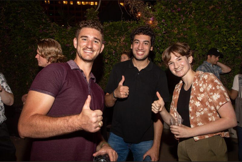 Three people smile for a photo at a party