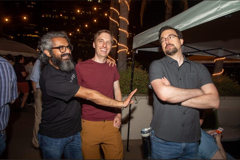 Three people smile for a photo at a party